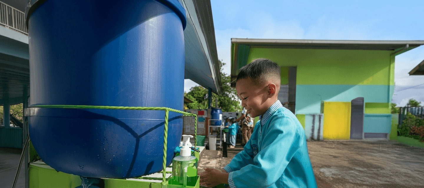 Anak-anak di sekolah dengan tangki air bersih